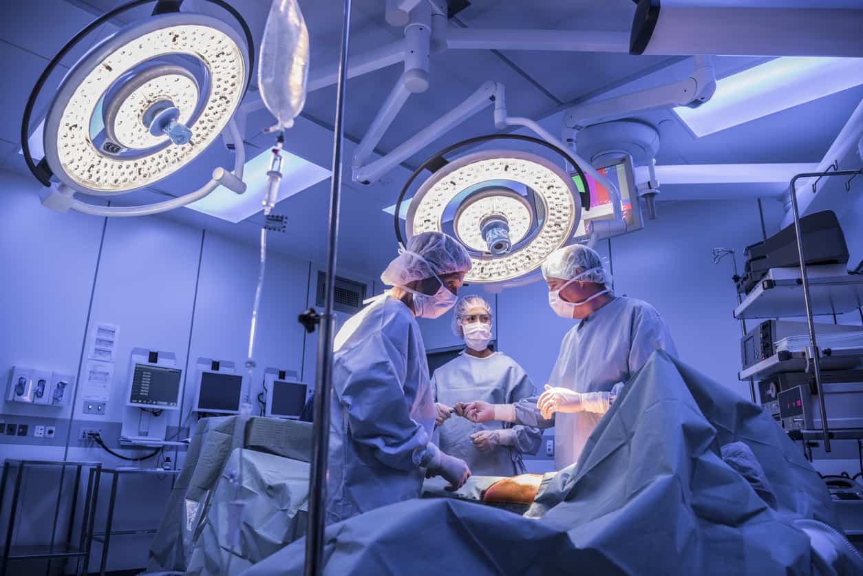 Surgeons operating on patient in operating theatre under lights
